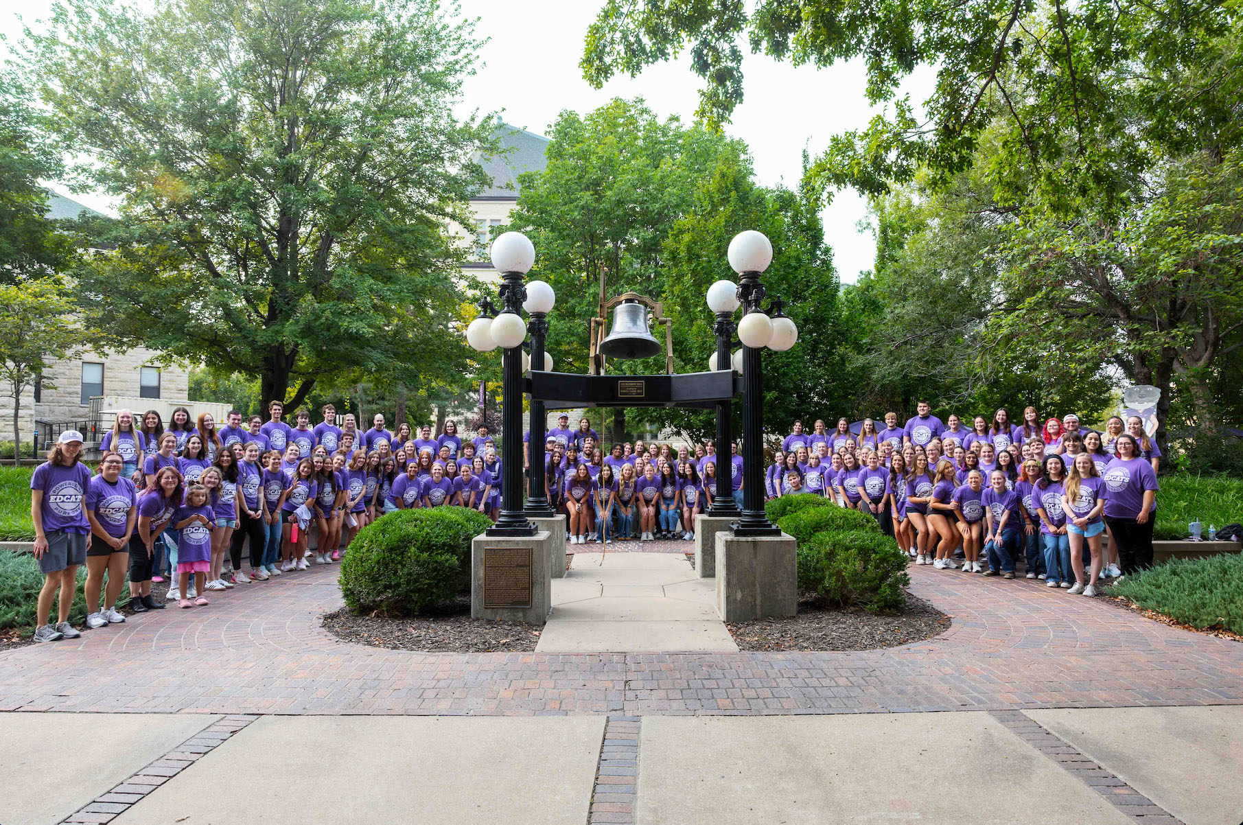 K-State College of Education students cheer while surrounding the Bluemont Bell